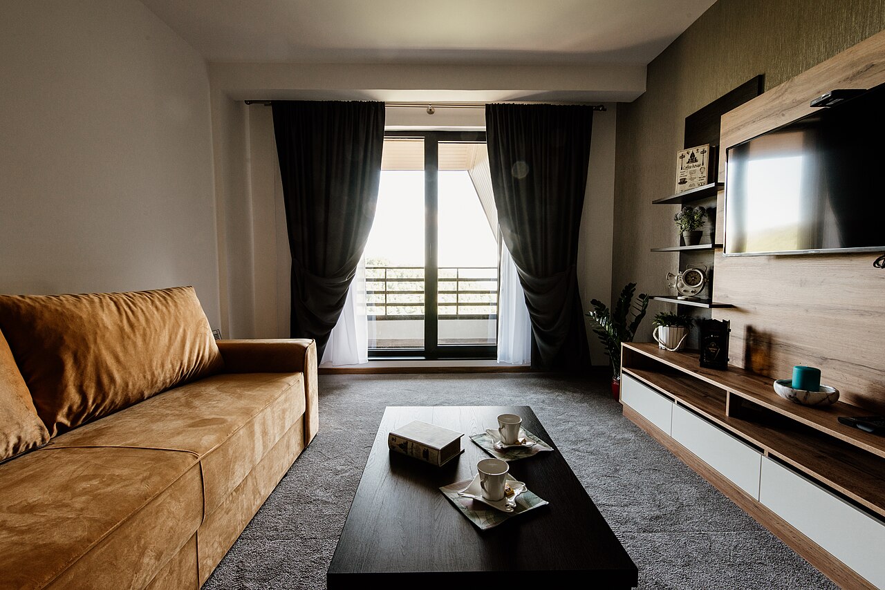 A bright, guest-ready living room with a sofa and a view outdoors